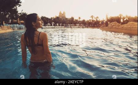 Parc aquatique Aquaventure une femme à pied admirez le coucher du soleil dans la piscine avec le panorama du parc aquatique de l'hôtel atlantis Banque D'Images