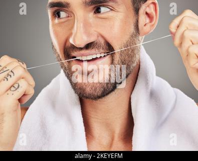 L'homme, la soie dentaire et les dents. Santé dentaire et hygiène pour le bien-être de la bouche, la publicité et le produit de nettoyage sur un fond gris studio. Modèle mâle Banque D'Images