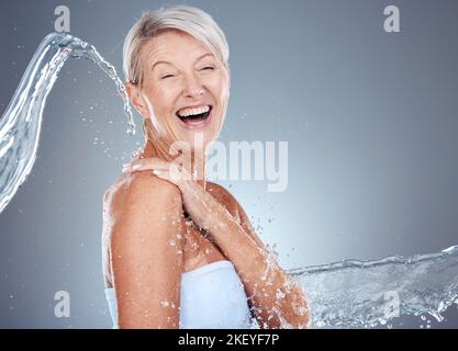 Éclaboussures d'eau, santé et portrait de femme âgée riant et heureux sur fond gris avec l'espace de maquette. Soin de la peau, bien-être et beauté, femme mûre Banque D'Images