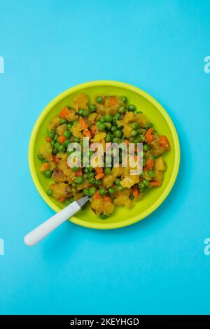 légumes mélangés pois, carottes, pomme de terre assiette enfant sur bleu Banque D'Images