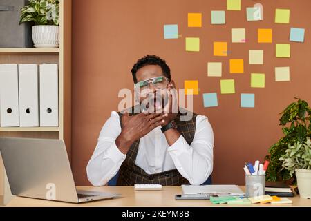 Portrait de l'entrepreneur fatigué du travail assis au bureau et bâilloir Banque D'Images
