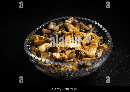 Gros plan de champignons marinés avec carottes dans un bol en verre sur fond noir. En-cas, nourriture Banque D'Images