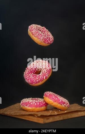 Mini beignets faits maison vitrés dans l'espace sur fond noir Banque D'Images
