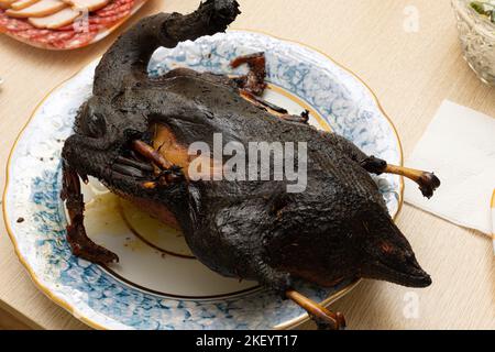 Carcasse d'oiseau brûlée sur l'assiette de service de la table à manger. Servir un plat gâté charmé. Femme de ménage louable et mauvais chef. Faire cuire la viande au four. Le principal est terrible Banque D'Images