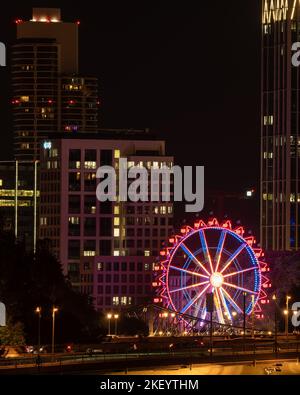 Une verticale de la ville de Francfort la nuit et la grande roue qui brillent devant les bâtiments Banque D'Images