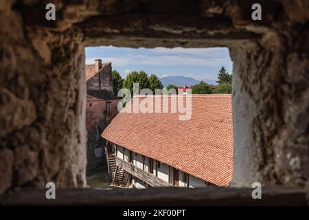 A travers l'échappatoire carrée du mur fortifié de l'église de Prejmer, la magnifique vue panoramique de Transylvanie s'ouvre, à partir du toit de la forteresse carrelée, Brasov, ROM Banque D'Images