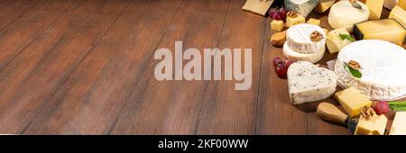 Différentes sortes de fromages. Plateau de fromages avec divers fromages, avec des raisins, des noix, un couteau à fromage et des épices, un espace de copie en bois Banque D'Images