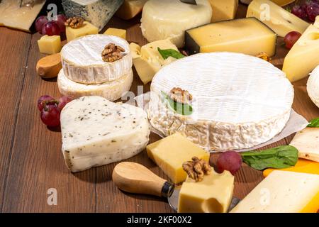 Différentes sortes de fromages. Plateau de fromages avec divers fromages, avec des raisins, des noix, un couteau à fromage et des épices, un espace de copie en bois Banque D'Images