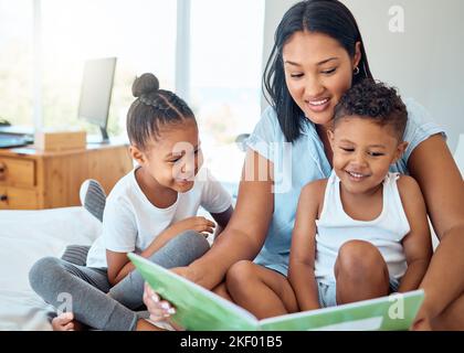 Mère lisant un livre à ses enfants dans une chambre à coucher pour se détendre, lier et apprendre dans leur maison familiale. Le bonheur, l'éducation et la femme en train de raconter des histoires Banque D'Images