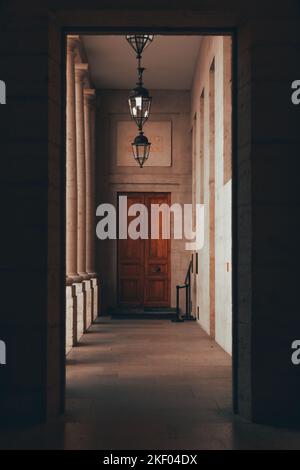 Un plan vertical de l'intérieur d'un couloir de bâtiment menant à une porte en bois marron Banque D'Images