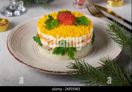 Salade feuilletée de fête Mimosa avec poisson en conserve, pommes de terre, fromage, carottes et œufs, garnie de caviar rouge et de feuilles de persil Banque D'Images