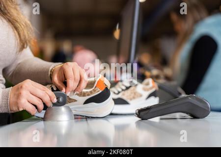 Un employé du magasin de vêtements retire l'alarme d'un vêtement Banque D'Images