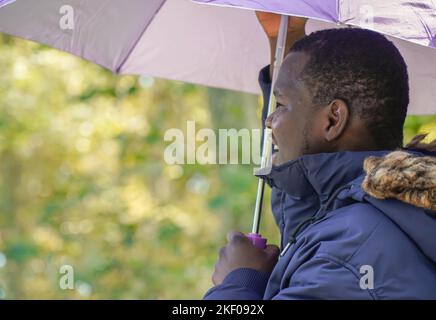 homme africain noir tenant un parapluie en hiver. migration espagnole Banque D'Images