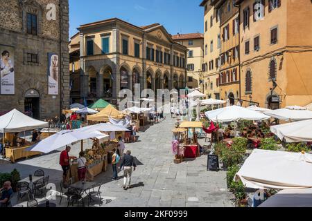 Étals du marché sur la Piazza Luca Signorelli avec Teatro Signorelli en arrière-plan dans la ville de Cortona en Toscane, Italie Banque D'Images