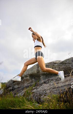 Vue latérale d'une femme de fitness qui fait de la course à haute intensité sur le flanc de la montagne Banque D'Images