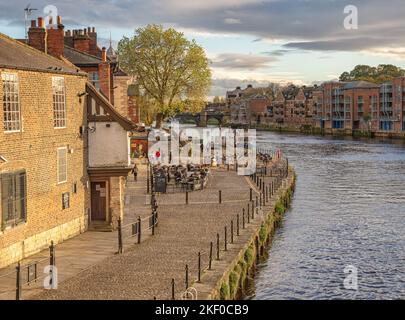 Pub Riverside à York. L'ancien bâtiment est à côté d'un chemin pavés et les clients sont assis sur des tables à l'extérieur. Un ciel nuageux est au-dessus. Banque D'Images