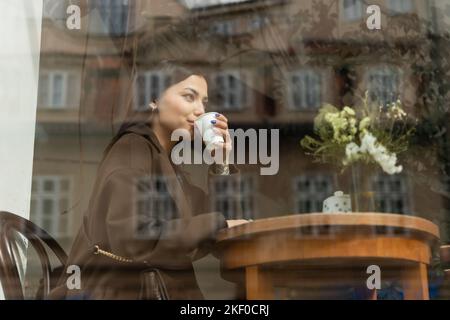 jeune femme en automne manteau boire du café près de la fenêtre dans le café de prague, image de stock