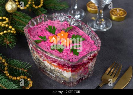 Salade russe traditionnelle de vacances hareng sous un manteau de fourrure dans un saladier transparent sur fond gris Banque D'Images