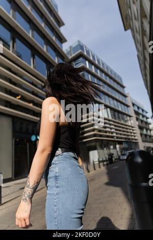 Vue arrière de la femme tatouée se tenant sur une rue urbaine floue à Prague, image de stock Banque D'Images