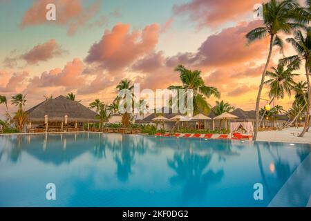 Luxe piscine à débordement coucher de soleil ciel dans un bord de mer d'été chaises de piscine hôtel complexe au paysage tropical. Plage tranquille vacances vibes Banque D'Images