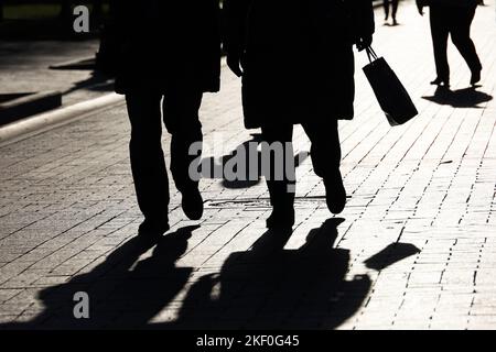 Silhouettes et ombres des gens sur la rue de la ville. Deux femmes en premier plan marchant sur le trottoir, concept de société et de population Banque D'Images