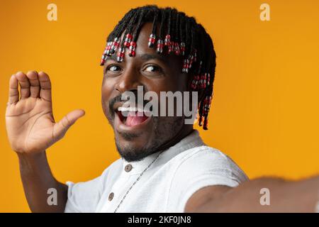 Un jeune homme africain portant des vêtements décontractés qui renonce à dire bonjour sur fond jaune Banque D'Images
