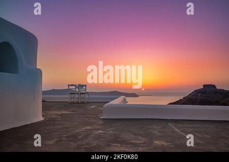 Architecture blanche sur l'île de Santorin, Grèce. Restaurant extérieur sous un paysage fantastique de coucher de soleil, chaises pour couple. Vue romantique sur le coucher du soleil, orange Banque D'Images
