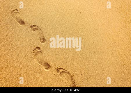 Plage, vagues et traces de pieds au coucher du soleil Banque D'Images