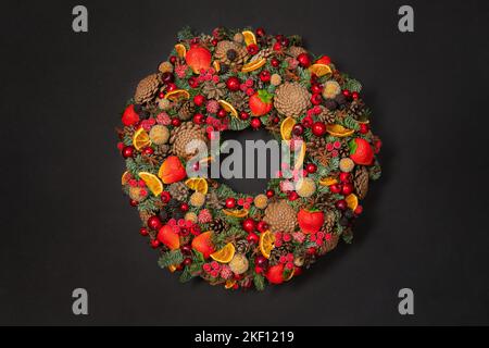 Couronne colorée sur fond noir. Guirlande décorée de fruits et de baies sur la surface sombre. Banque D'Images