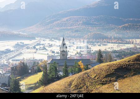 Belle vue sur la vallée de l'Engadine, en Suisse, le matin d'automne ensoleillé. Église catholique 'Herz Jesu Kirche' dans la ville de Samedan en premier plan. Banque D'Images
