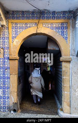 Femme en robe locale à l'entrée du marché de l'or d'Essaouira Banque D'Images