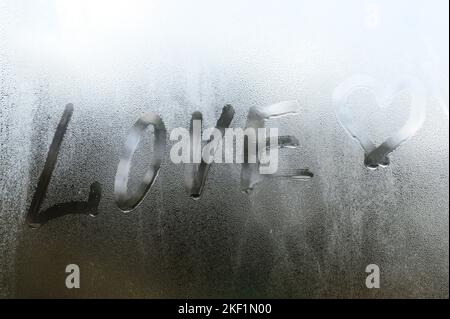 l'inscription du mot amour avec un coeur sur une texture avec condensation sur le verre, une réaction à un changement soudain de température sur le verre, Banque D'Images