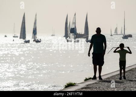 Touristes et voiliers en silhouette sur la Promenade du Tejo, le Tage Lisbonne, Portugal. Banque D'Images