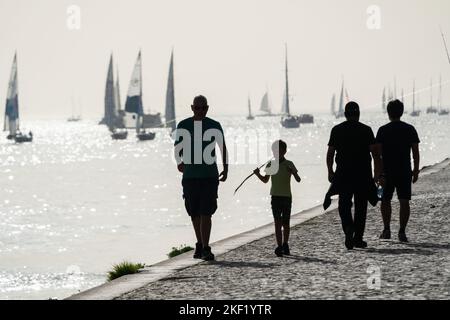 Touristes et voiliers en silhouette sur la Promenade du Tejo, le Tage Lisbonne, Portugal. Banque D'Images