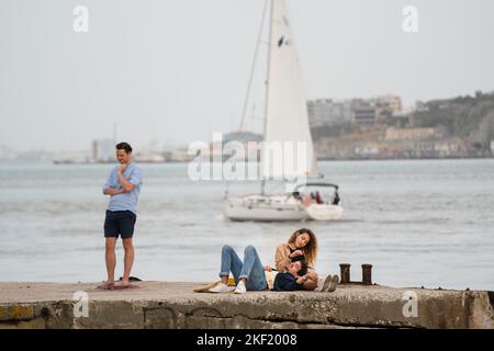 Un homme pose pour une photo par un jeune couple romantique sur la promenade du Tejo, le Tage de Lisbonne, Portugal. Banque D'Images