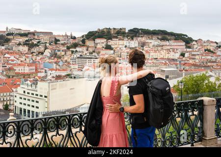 Un jeune couple partage une étreinte romantique au Miradouro de São Pedro de Alcântara à Lisbonne, Portugal. Ce mirador offre une vue panoramique. Banque D'Images