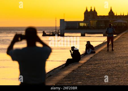 Les touristes apprécient la vue et l'atmosphère du soir sur le Tejo Promenade Sea Wall dans le quartier de Belem à Lisbonne, Portugal. Banque D'Images
