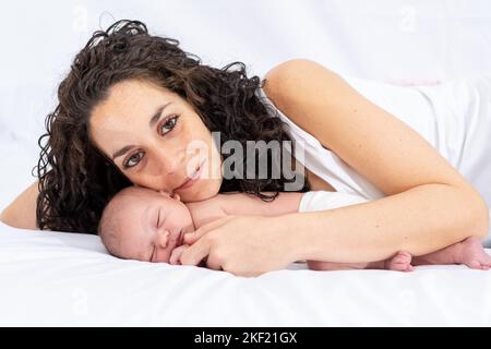 portrait de jeune mère souriante embrassant son bébé endormi allongé dans le lit. concept famille et attention et soins du nouveau-né Banque D'Images