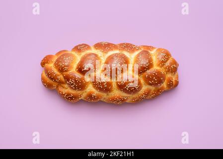 Directement au-dessus de la vue avec un pain de challah maison minimaliste sur une table pourpre. Pain tressé, une recette juive traditionnelle, sur un dos coloré Banque D'Images