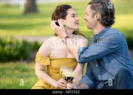 Couple amoureux lors d'un pique-nique dans Forest Park. L'homme joue une guitare pour sa femme. Banque D'Images