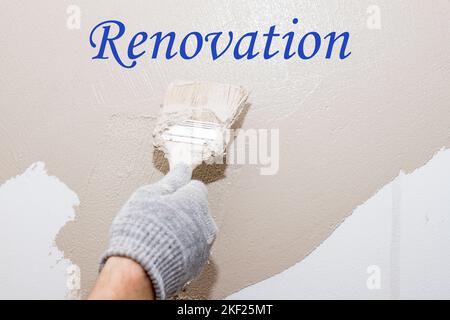 Pinceau, gros plan peintre ouvrier peinture sur mur de surface peinture appartement, rénovation avec peinture beige. Rénovation descriptif Banque D'Images