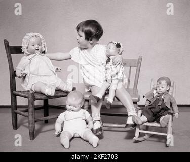 1930S PETITE FILLE BRUNETTE JOUANT AVEC DES POUPÉES SE FAISANT ASSEOIR SES DIFFÉRENTES POUPÉES DANS DES CHAISES SUR SES GENOUX OU SUR LE SOL PAR SES PIEDS - J4616 HAR001 HARS B&W LAP BRUNETTE OBJECTIFS PORCELAINE MODÈLES CONNEXION ÉLÉGANT DIVERS OU COLLECTIBLES CROISSANCE JUVÉNILES TOGETHERNESS NOIR ET BLANC CAUCASIEN ETHNICITÉ COLLECTABLE HAR001 À L'ANCIENNE Banque D'Images