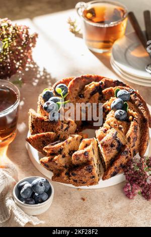 Gâteau aux myrtilles en tranches décoré de baies et de thé, concept de petit déjeuner festif ensoleillé le matin, temps de thé. Orientation verticale Banque D'Images