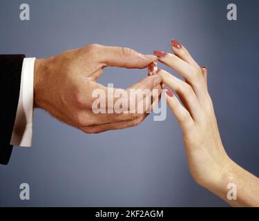 1960S MAIN DE MARIÉ MISE DE L'ANNEAU DE LA BANDE DE MARIAGE SUR LA MAIN DE LA MARIÉE - KB5485 HAR001 HARS ESPACE DE COPIE AMITIÉ FEMMES MARIAGE PERSONNES BIENVEILLANTE HOMMES CÉRÉMONIE BONHEUR ÉPOUSES COUTUME EXCITATION TRADITION NUPTIAL NUPTIALS OCCASION MARIAGE CONNEXION CONCEPTUELLE GROS PLAN RITE DE PASSAGE WED PERSONNEL ATTACHEMENT PROMESSE AFFECTION ENGAGEMENT BETROTHAL COOPÉRATION ÉMOTION MARIAGE ÉPOUSES JEUNE HOMME ADULTE JEUNE FEMME ADULTE MARIÉE ET MARIÉ CAUCASIEN L'ETHNICITÉ SE FAIT ENTRE LES MAINS DE SEULEMENT HAR001 PERSONNES Banque D'Images