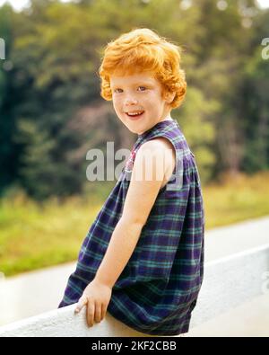 1960S PORTRAIT SOURIANT FRECKLE-VISAGE CURLY ROUGE CHEVEUX FILLE ASSISE SUR LA CLÔTURE PORT À CARREAUX SANS MANCHES ROBE REGARDANT L'APPAREIL-PHOTO - KJ3721 HAR001 HARS COPIE ESPACE DEMI-LONGUEUR PLAID FRECKLES EXPRESSIONS ÉTÉ CONTACT DES YEUX BONHEUR GAI BOUCLES RICHEMENT REDHEAD CHEVEUX RAILLÉ SOURIRES ROUGE CHEVEUX JOYEUX CROISSANCE AGRÉABLE JEUNES SAISON PERSONNABLE ORIGINE ETHNIQUE CAUCASIENNE FRECKLE-FACE HAR001 OLD FASHIONED SHORT HAIR SANS MANCHES Banque D'Images