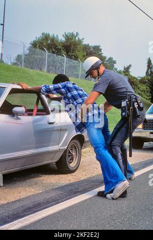 1970S POLICIER FRISKING AFRICAIN-AMÉRICAIN HOMME SPREAD-EAGLED PENCHÉE SUR LA VOITURE PENDANT L'ARRÊT DE LA CIRCULATION - KP3044 HAR001 HARS PROTÈGENT LA PROTECTION AFRO-AMÉRICAINE AFRICAN-AMERICAN ET AUTOMOBILES EXCITATION LEADERSHIP PUISSANT NOIR ETHNICITÉ AUTORITÉ OCCUPATIONS UNIFORMES AUTOMOBILES ÉCHAPPER VÉHICULES OFFICIERS POLICIERS COOPÉRATION COPS FRISKING MI-ADULTE HOMME MI-ADULTE JEUNE ADULTE HOMME BADGE BADGES RACE BLANCHE HAR001 AFRO-AMÉRICAINS À L'ANCIENNE Banque D'Images