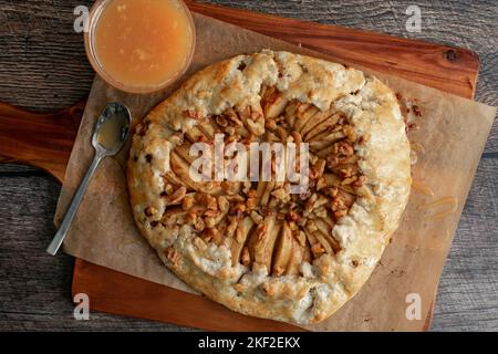 Vue en hauteur d'une tranche de galette de pomme au caramel salé : une galette de pomme fraîchement cuite sur une planche à découper recouverte de papier parchemin Banque D'Images