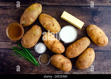 Ingrédients de pommes de terre écrasés sur une table rustique en bois : pommes de terre Russet, crème, beurre et autres ingrédients pour le plat de pommes de terre écrasé Banque D'Images