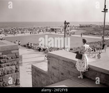 1950S FEMME DEBOUT SUR LES ESCALIERS SURPLOMBANT JONES BEACH LONG ISLAND NEW YORK USA - R3049 HAR001 HARS FEMMES PERSONNES ÉTATS-UNIS D'AMÉRIQUE HOMMES B&W AMÉRIQUE DU NORD L'ÉTÉ L'AMÉRIQUE DU NORD LE TEMPS HORS DE L'AVENTURE GRAND ANGLE LOISIR VOYAGE ESCAPADE EXCITATION LOISIRS VACANCES NYC LONG ISLAND NEW YORK VILLES PUBLIC PARK JONES NEW YORK CITY BARRIER ISLAND OCÉAN ATLANTIQUE SURPLOMBANT LA DÉTENTE VACANCES DE SAISON NOIR ET BLANC HAR001 OLD FASHIONED STATE PARK Banque D'Images