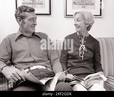 1970S COUPLE ASSIS SUR UN CANAPÉ LISANT DES MAGAZINES EN PARLANT À UN AUTRE HOMME SOURIANT PORTANT UNE CEINTURE BLANCHE DE CHEMISE À POIS - S20508 HAR001 HARS TRAVAIL D'ÉQUIPE INFORMATION FORTE JOIE HEUREUSE STYLE DE VIE CEINTURE SATISFACTION FEMMES MARIÉE ÉPOUX ÉPOUX SAINTETÉ VIE À LA MAISON COPIE ESPACE AMITIÉ DEMI-LONGUEUR FEMMES PERSONNES S'OCCUPANT HOMMES EXPRESSIONS B&W PARTENAIRE DOT BONHEUR GAI LOISIRS POLKA CONFORTABLE AUX MAGAZINES SOURIRES CONTENU DE CONNEXION JOYFUL ÉLÉGANT ATTACHEMENT PERSONNEL AFFECTION UNE AUTRE COOPÉRATION ÉMOTION MI-ADULTE MI-ADULTE HOMME MI-ADULTE FEMME TOGETHERNESS FEMMES À LA MAISON NOIR ET BLANC Banque D'Images